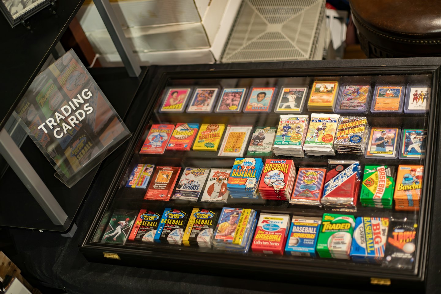Vintage trading cards and sports packs displayed in a glass case.